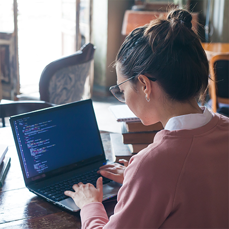 A woman developing code on a laptop.